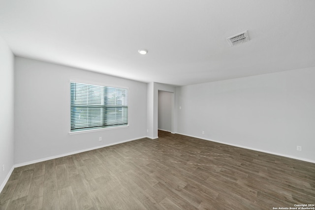 unfurnished room featuring wood finished floors, visible vents, and baseboards