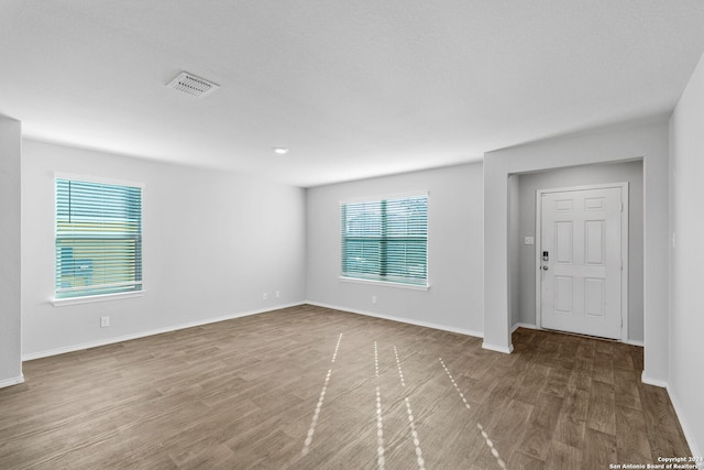 spare room with baseboards, visible vents, and wood finished floors