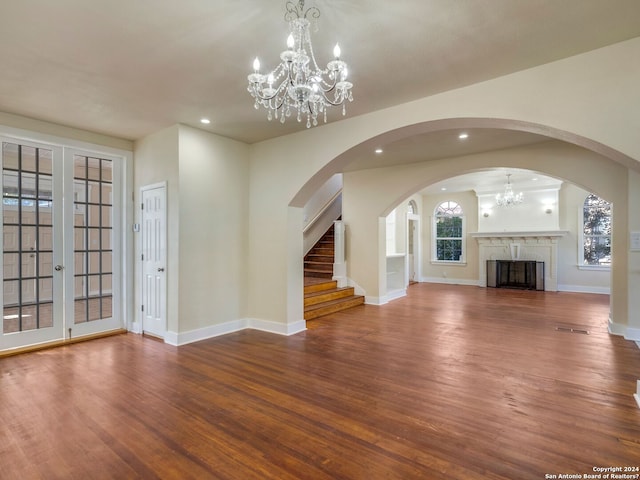 unfurnished living room featuring recessed lighting, an inviting chandelier, baseboards, and wood finished floors