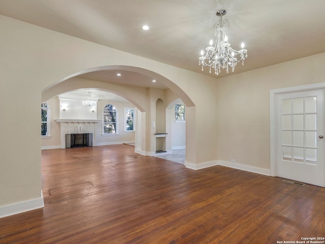 unfurnished living room with wood finished floors, visible vents, and an inviting chandelier