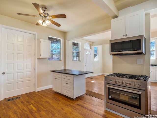 kitchen featuring stainless steel appliances, wood finished floors, visible vents, white cabinets, and dark countertops