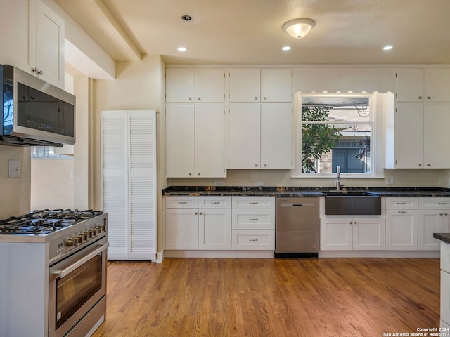 kitchen with stainless steel appliances, recessed lighting, white cabinetry, a sink, and light wood-type flooring