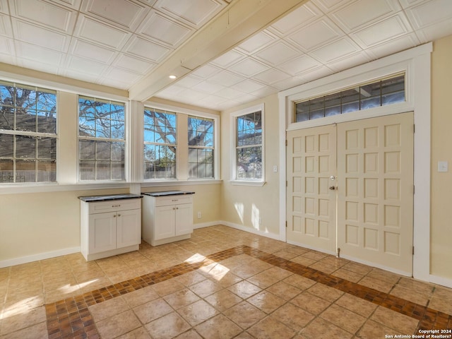 entrance foyer with light tile patterned floors, an ornate ceiling, and baseboards