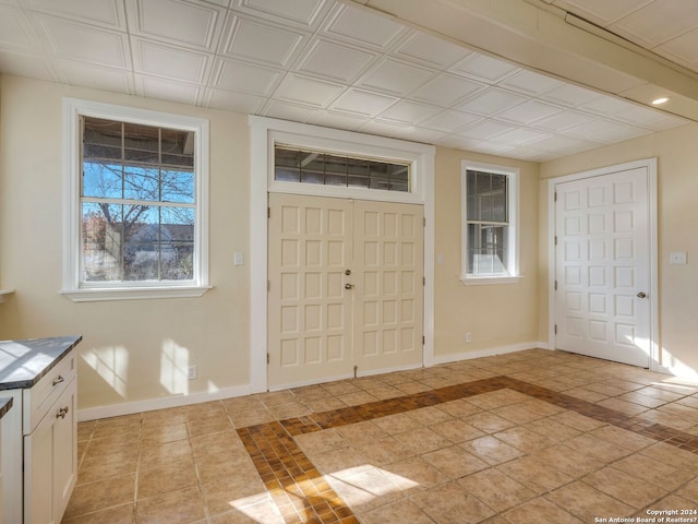 entryway featuring an ornate ceiling, baseboards, and light tile patterned floors