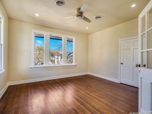 unfurnished room featuring a ceiling fan, dark wood finished floors, visible vents, and baseboards