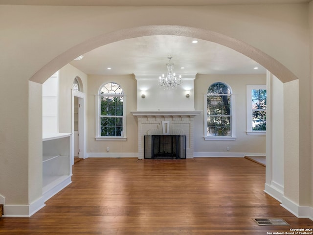 unfurnished living room with built in features, visible vents, a fireplace, and wood finished floors