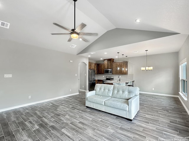 living room with arched walkways, wood finish floors, lofted ceiling, visible vents, and ceiling fan with notable chandelier