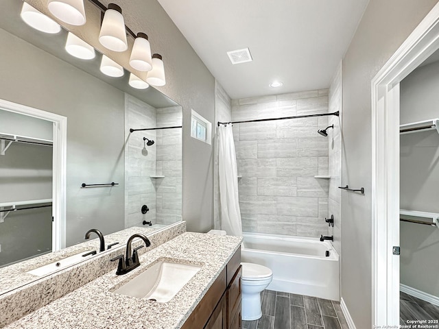 full bathroom with toilet, wood finish floors, visible vents, a spacious closet, and shower / tub combo with curtain