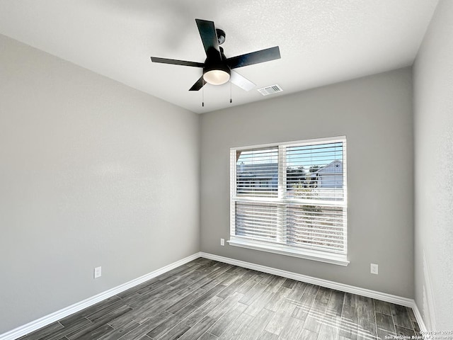 unfurnished room with a ceiling fan, baseboards, visible vents, and dark wood-type flooring