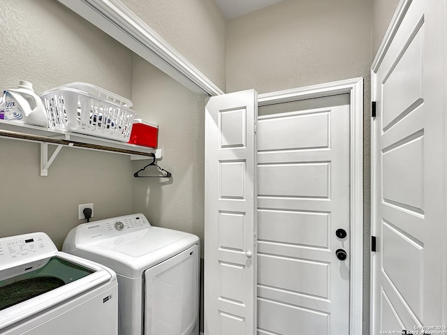 laundry area featuring laundry area, a textured wall, and separate washer and dryer