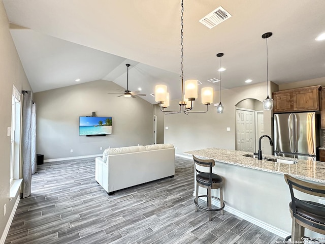 kitchen with visible vents, arched walkways, open floor plan, freestanding refrigerator, and a sink