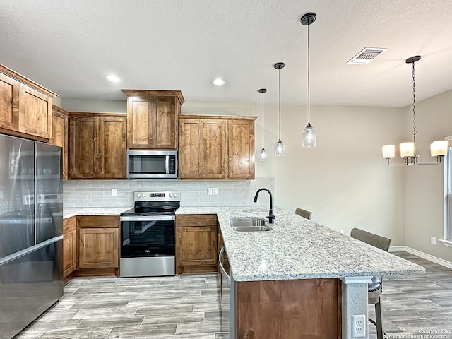 kitchen with visible vents, a breakfast bar area, a peninsula, stainless steel appliances, and a sink