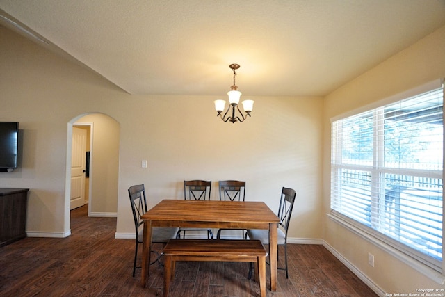 dining area featuring arched walkways, baseboards, wood finished floors, and a chandelier