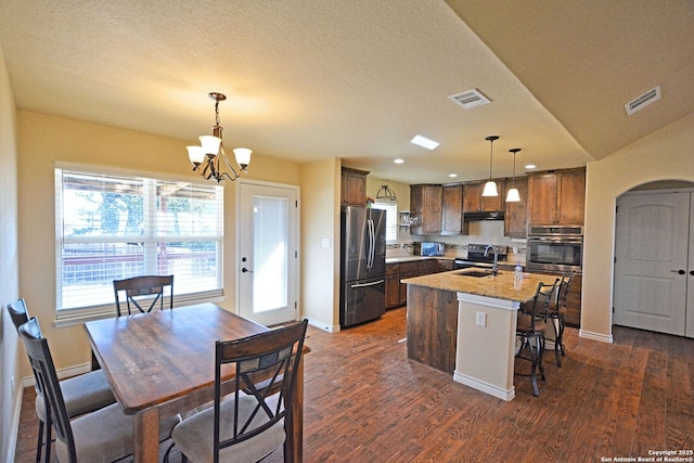 kitchen featuring visible vents, arched walkways, stainless steel appliances, and a sink