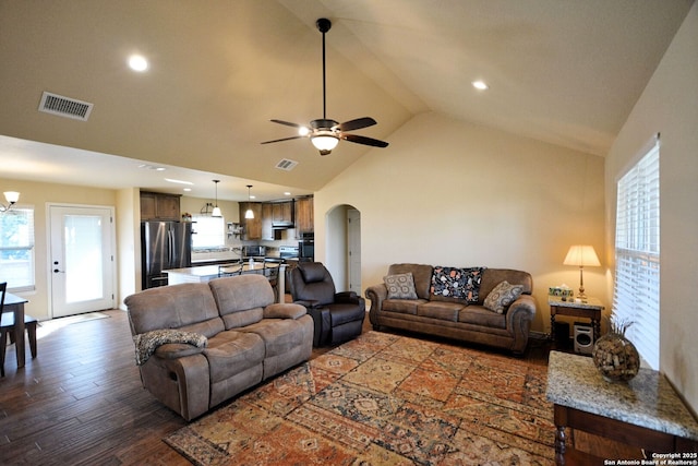 living room featuring arched walkways, ceiling fan with notable chandelier, wood finished floors, and visible vents