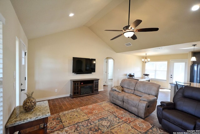 living room featuring baseboards, visible vents, arched walkways, wood finished floors, and ceiling fan with notable chandelier