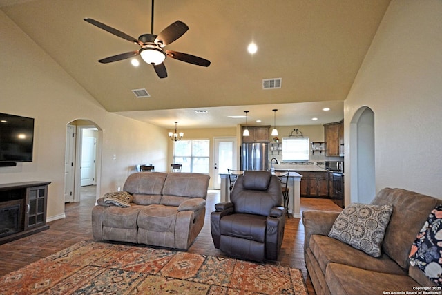 living room featuring arched walkways, visible vents, wood finished floors, high vaulted ceiling, and ceiling fan with notable chandelier