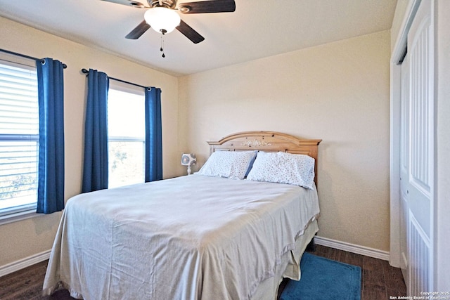 bedroom with ceiling fan, multiple windows, baseboards, and wood finished floors