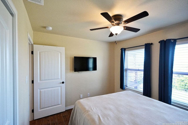 bedroom with dark wood-type flooring, multiple windows, baseboards, and a ceiling fan