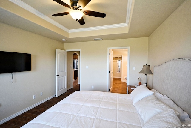 bedroom with crown molding, visible vents, a raised ceiling, and wood finished floors