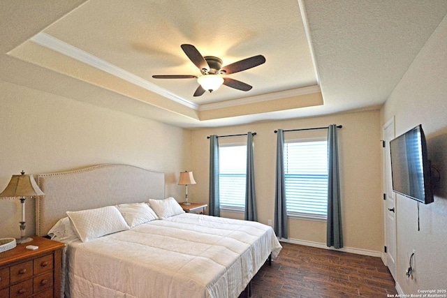 bedroom featuring dark wood-style flooring, a raised ceiling, ornamental molding, a ceiling fan, and baseboards