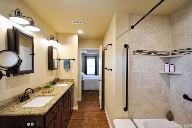 bathroom featuring double vanity, visible vents, a sink, and wood finished floors