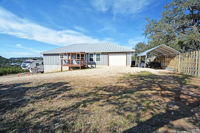 view of front facade with a standing seam roof, metal roof, driveway, a detached carport, and board and batten siding