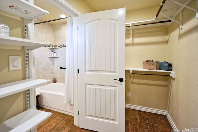 bathroom featuring shower / bath combination with curtain, wood finished floors, and baseboards