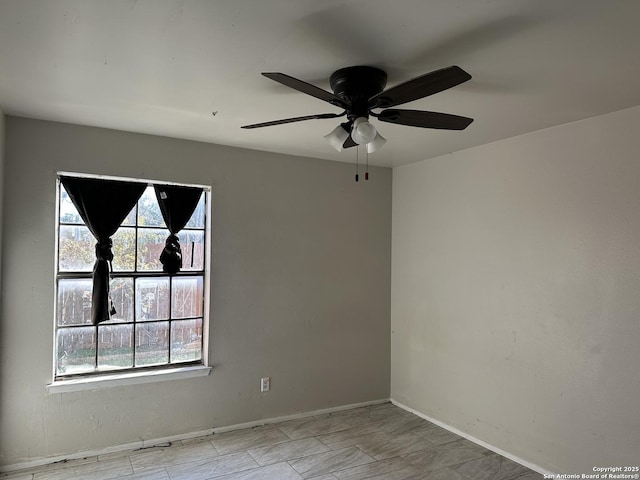 unfurnished room with ceiling fan and baseboards