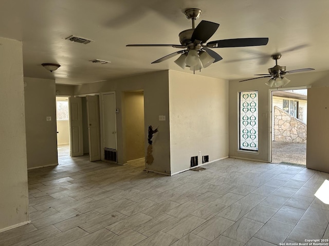 empty room featuring a wealth of natural light, visible vents, and wood finished floors