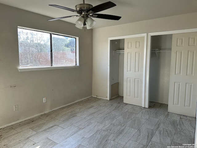 unfurnished bedroom with ceiling fan and two closets