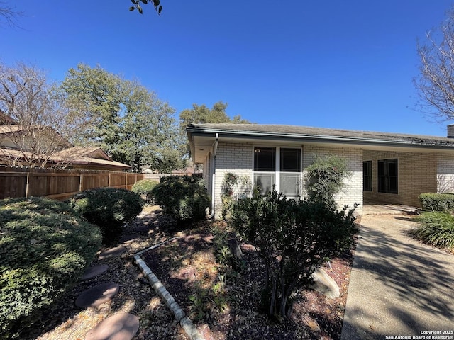 view of side of property featuring brick siding and fence