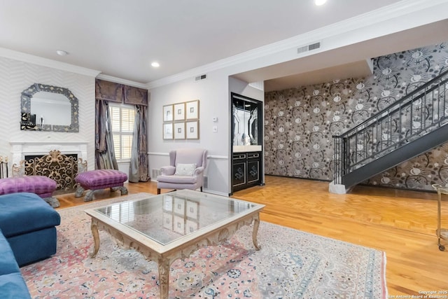 living area with ornamental molding, wood finished floors, stairs, a fireplace, and recessed lighting