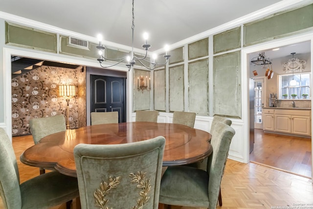 dining space with parquet floors, ornamental molding, visible vents, and a decorative wall