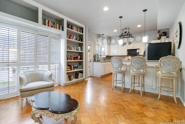 kitchen featuring a breakfast bar, recessed lighting, hanging light fixtures, freestanding refrigerator, and white cabinets