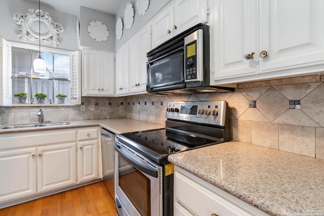 kitchen with stainless steel appliances, decorative backsplash, white cabinetry, a sink, and light wood-type flooring