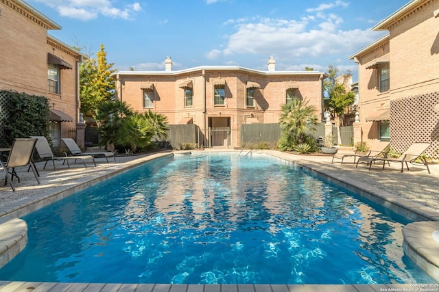 pool with a patio and fence