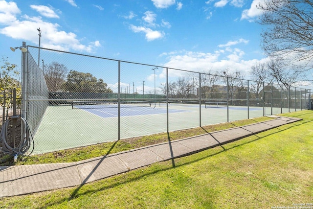 view of tennis court with fence and a lawn