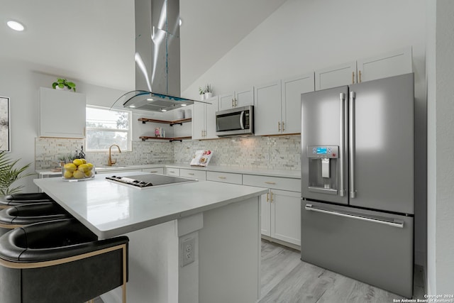 kitchen featuring lofted ceiling, stainless steel appliances, ventilation hood, light countertops, and a sink