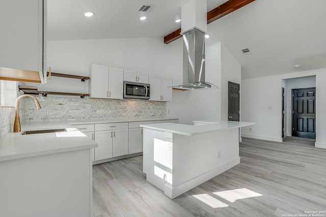 kitchen with white cabinets, stainless steel microwave, a sink, open shelves, and backsplash