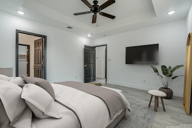 bedroom featuring visible vents, a raised ceiling, baseboards, light wood-style flooring, and recessed lighting