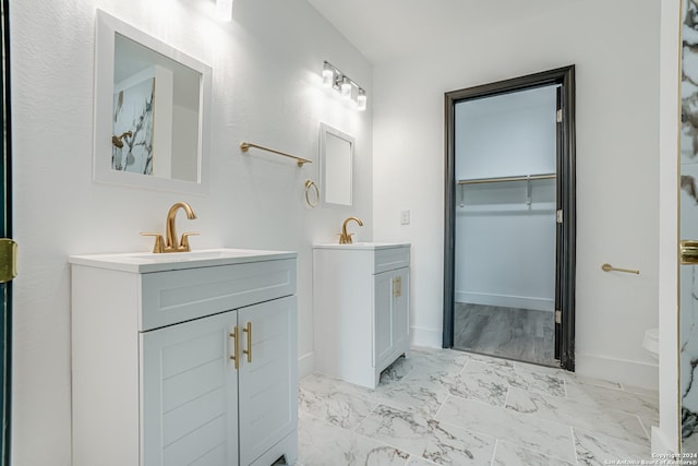 full bathroom featuring a sink, marble finish floor, two vanities, and baseboards