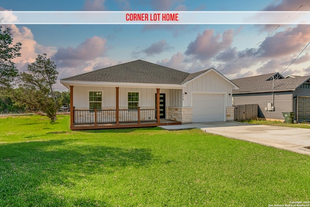 ranch-style house featuring a garage, a shingled roof, concrete driveway, a front lawn, and a porch