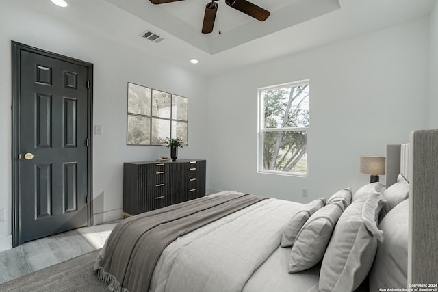 bedroom with visible vents, ceiling fan, a tray ceiling, light wood-style floors, and recessed lighting