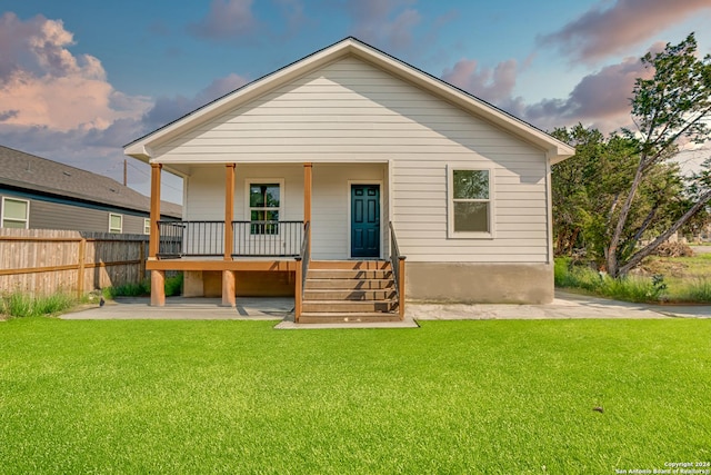 back of house featuring a yard, a porch, and fence