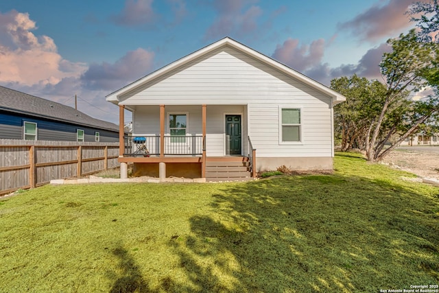 back of property with a porch, a yard, and fence