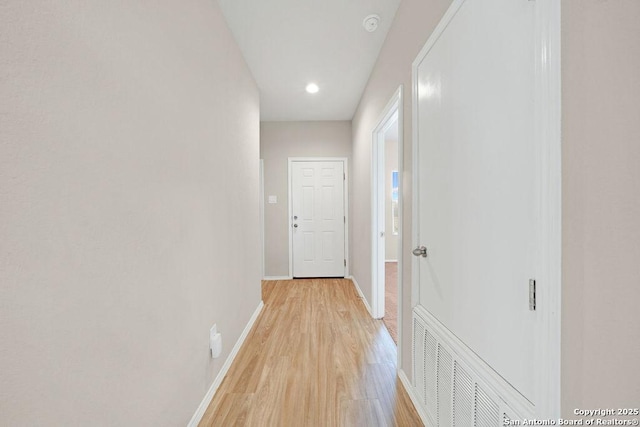 hall featuring baseboards, visible vents, and light wood-style floors