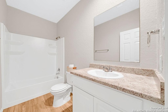 full bathroom featuring a textured wall, toilet, shower / tub combination, wood finished floors, and vanity