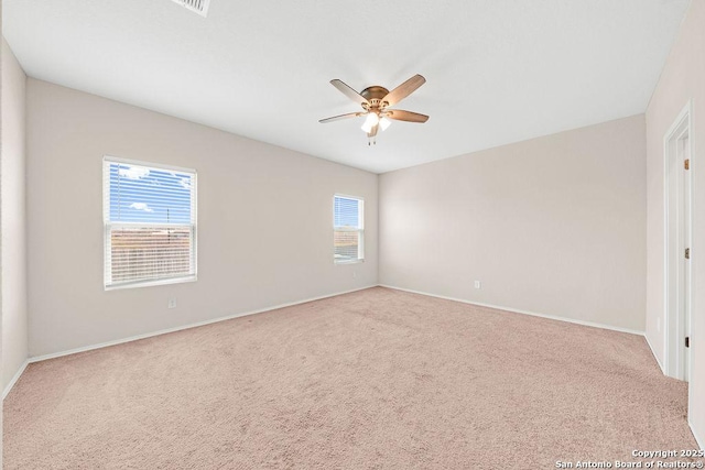 carpeted empty room with a ceiling fan and baseboards