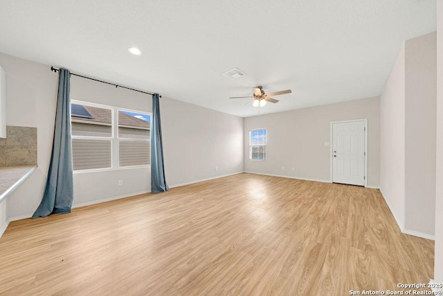 spare room with light wood-style floors, baseboards, visible vents, and a ceiling fan